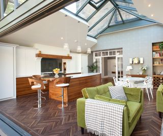 orangery kitchen extension with detailed roof lantern, herringbone wooden floor and an open plan kitchen diner and living room space