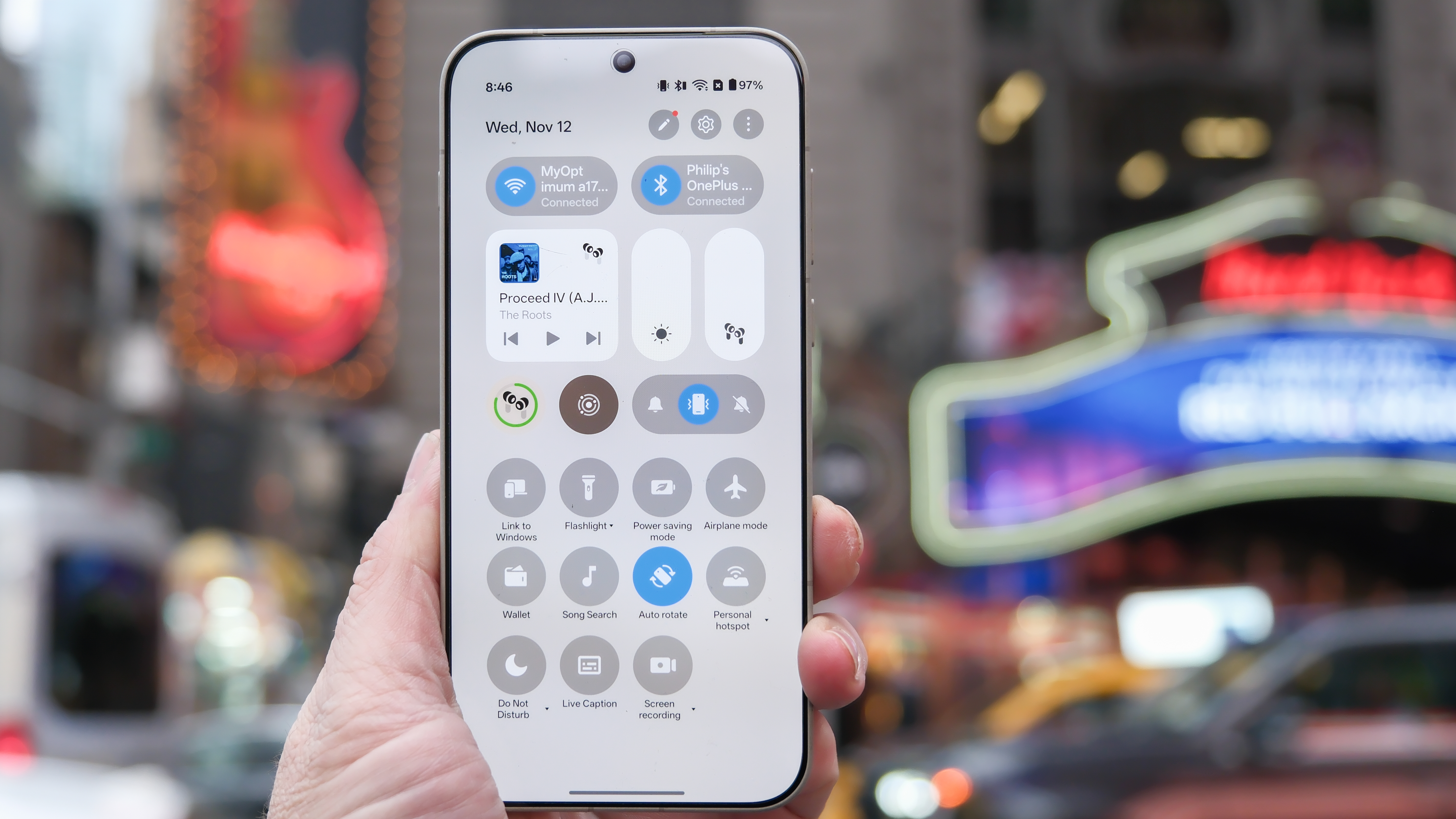 OnePlus 15 in Times Square New York City on the busy street showing the cameras and sides of the phone in addition to home screen panels and Settings menus