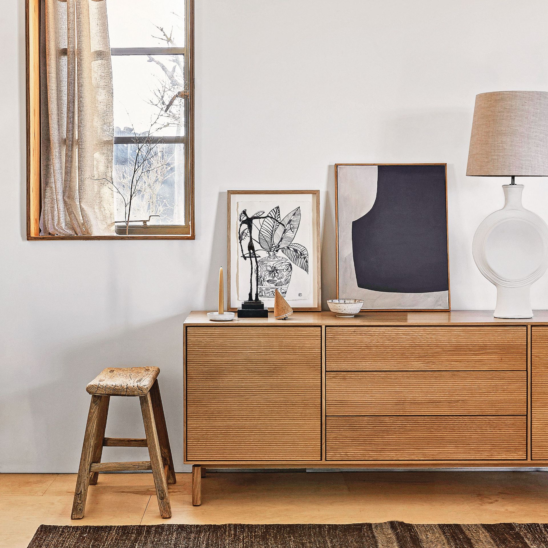 Wooden sideboard on a wooden floor, black rug and grey walls
