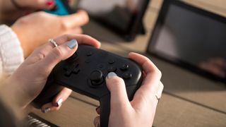 The best Nintendo Switch accessories; a photo of a girl playing using a Switch Pro controller