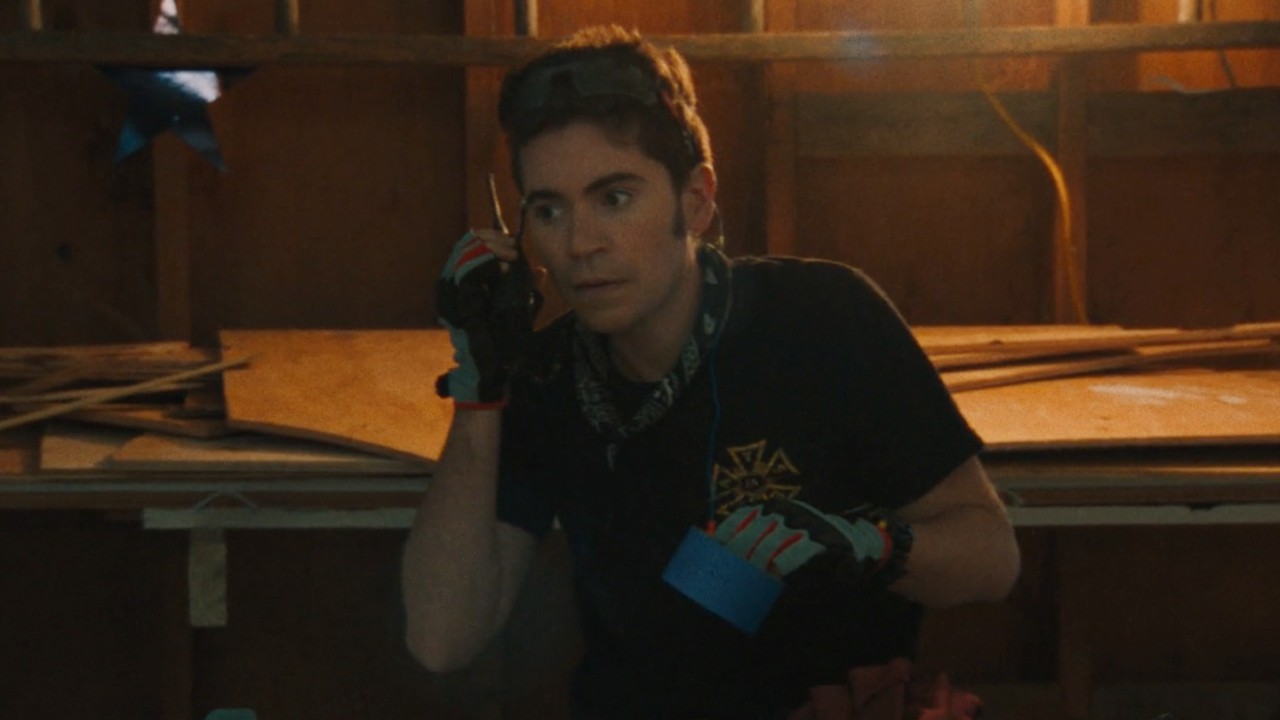 Noah Galvin talking into a walkie talkie in Theater Camp.