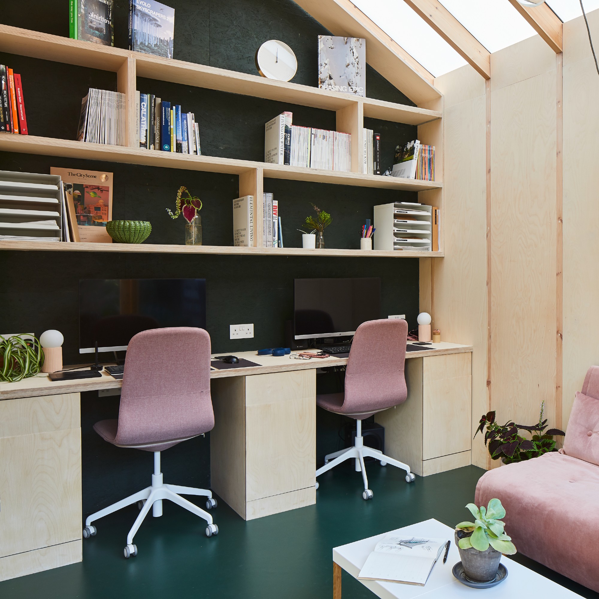 A home office with double desks, built-in floating storage and pink desk chairs