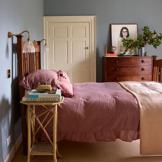 Painted bedroom with pink bedding, bedside table, and dark wood dressers