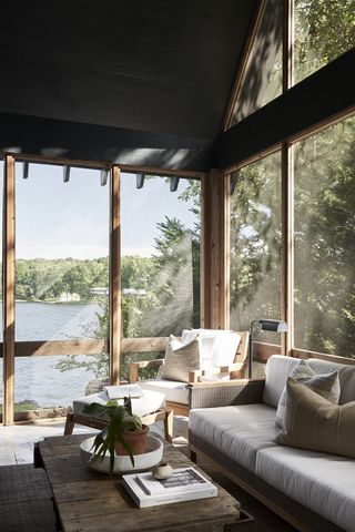 screened in porch set on a lakeside with a grey sofa