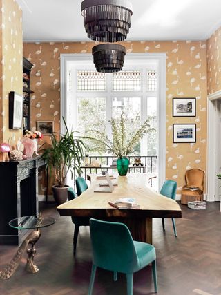 Dining room with flamingo wallpaper and green velvet chairs