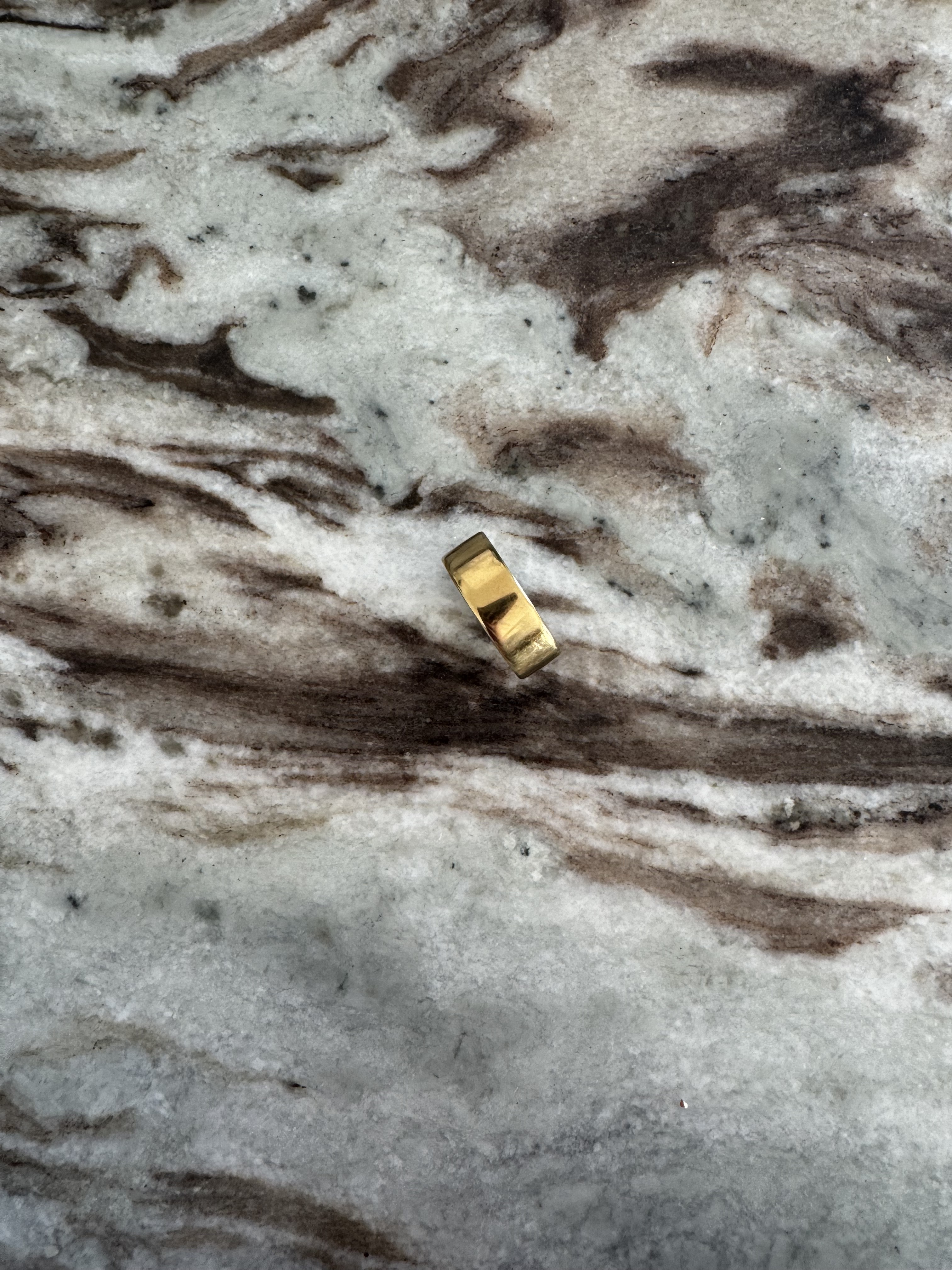 A photo of the Oura Ring 4 in Gold, size 7, on a marble surface