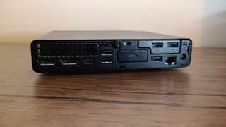 A black compact HP EliteDesk 800 desktop PC sitting on a brown wooden table