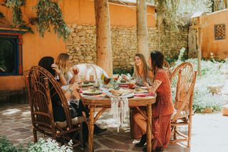 Four women sit outside in a courtyard at Adobe & Pines Inn in Taos, New Mexico, enjoying cocktails