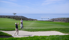 A golfer hits from a fairway bunker