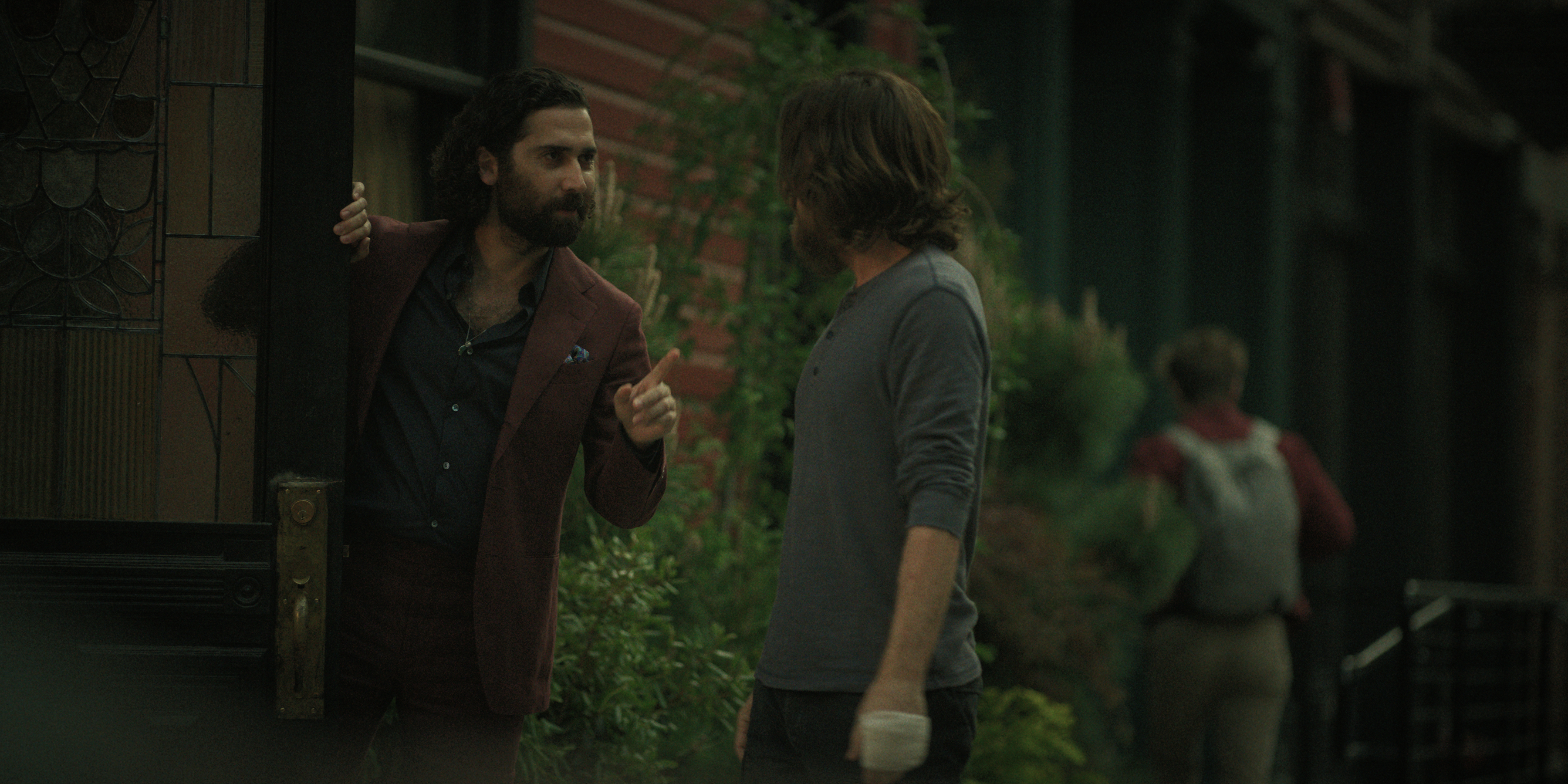 Amir Malaklou as naveen having a tense conversation outside of a building with jason bateman as vince in black rabbit
