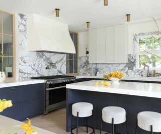 kitchen with blue cabinets and white cooker hood marble backsplash