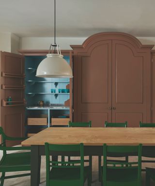 kitchen with cabinetry painted in brown and blue with rectangular wooden table and green chairs