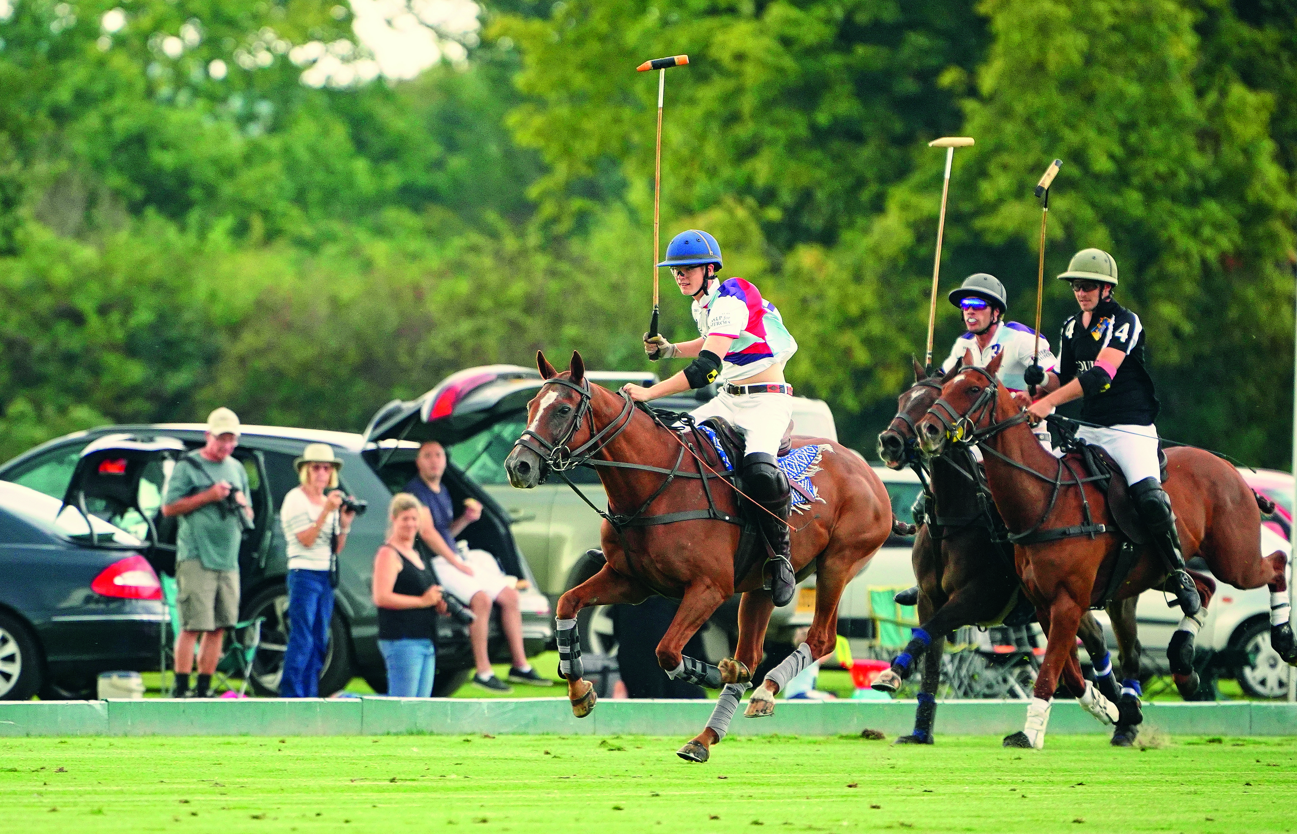 People on horses, riding around at speed, doing polo things like hitting a small ball with a big stick