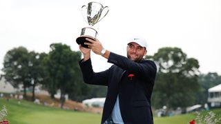 Scottie Scheffler lifts the 2024 Travelers Championship trophy after his victory over Tom Kim in a play-off round.