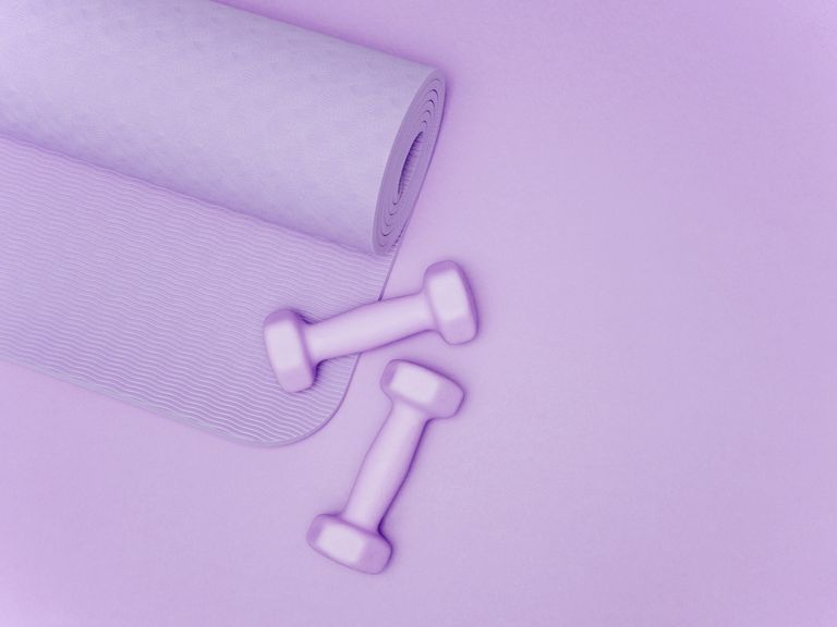 Yoga mat and dumbbells on purple background, dumbbells for women