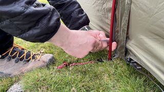 A pair of hands adjusting the poles while pitching an MSR Tindheim 2 tent.