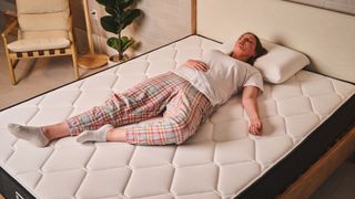 A person lies in a back sleeping position on top of the Plank Firm mattress on the Extra Firm side