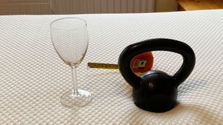 A wine glass, weight and tape measure on the Nectar Premier Hybrid mattress