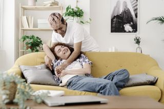 A non-binary couple hugging on the sofa