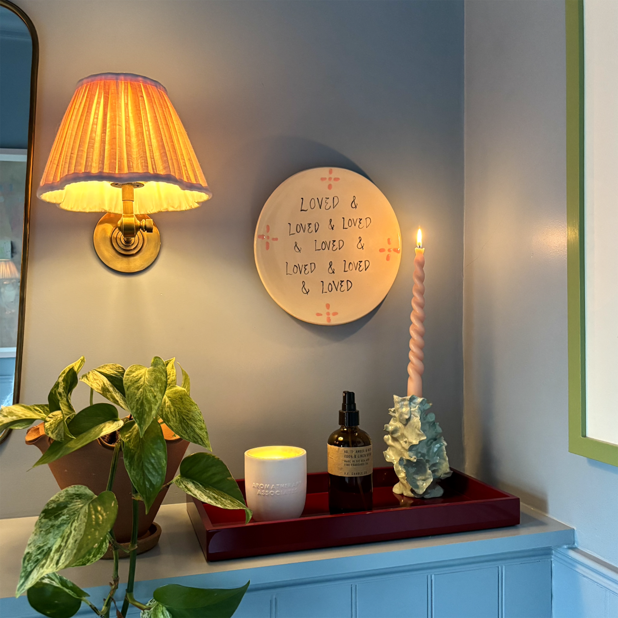 blue bathroom shelf styled with a tray holding a candlestick and candle