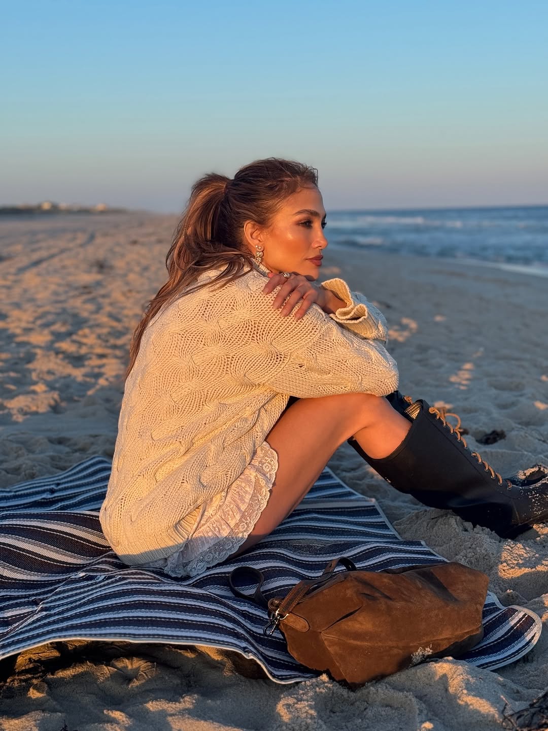 Jennifer Lopez posted on Instagram in a cardigan, lace bloomers/skirt, and lace-up knee-high boots