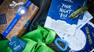 A Think Outside box is displayed with a star wheel, informational packet, flash cards, and a small child's carabiner clip.