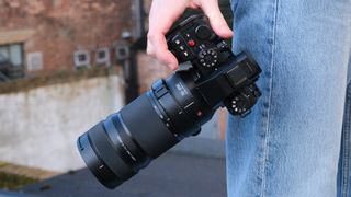 Panasonic Lumix S1R II camera with 70-200mm lens attached held by a person's side in one hand