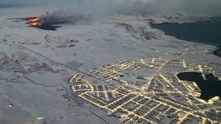 The evacuated Icelandic town of Grindavik (R) is seen as smoke billow and lava is thrown into the air from a fissure during a volcanic eruption on the Reykjanes peninsula 3 km north of Grindavik, western Iceland on December 19, 2023.