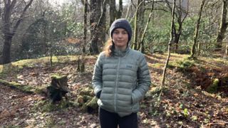 A hiker in the woods wearing the Helly Hansen Verglas 2.0 down jacket