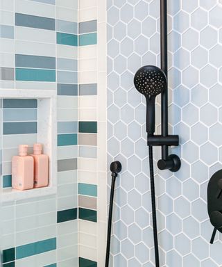 shower with two accent walls, one shades of blue small subway tiles, pale blue hex tiles on other side, black shower