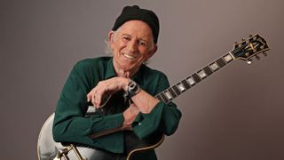 Keith Richards wears a dark green shirt and beanie and cradles his black 1960 Gibson ES-355.