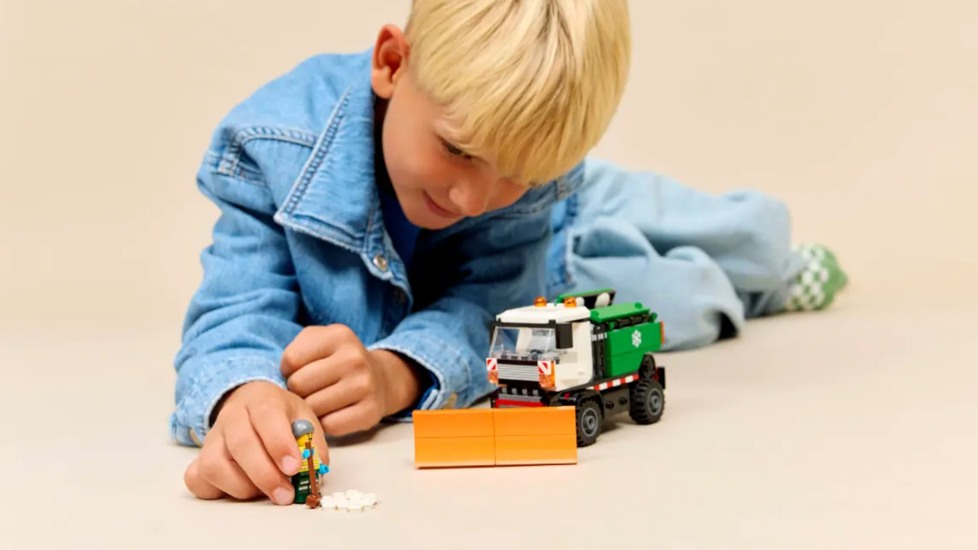 A child plays with the Lego Snowplough set whilst lying on the ground