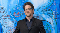 Jason Newsted in a suit in front of a surrealist blue painting