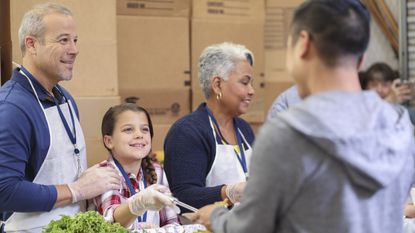 A young girl helps serve food at a soup kitchen.