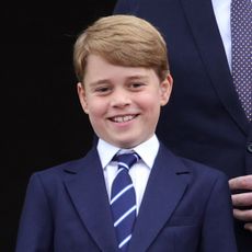 Prince George smiles in a suit and tie in the Royal Box at Wimbledon