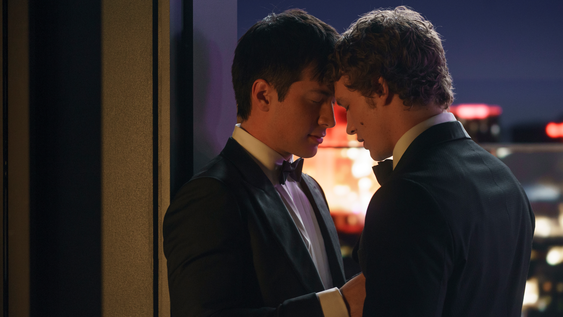 Two men (Hudson Williams as Shane Hollander and Connor Storrie as Ilya Rozanov) stand closely in front of a city skyline at night, in the TV show &#039;Heated Rivalry.&#039;