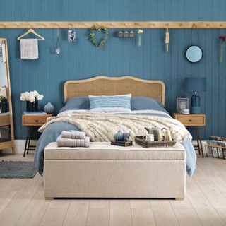Blue wood panelled bedroom, country style, wood flooring, wall mounted peg rail, bed position with headboard against a wall