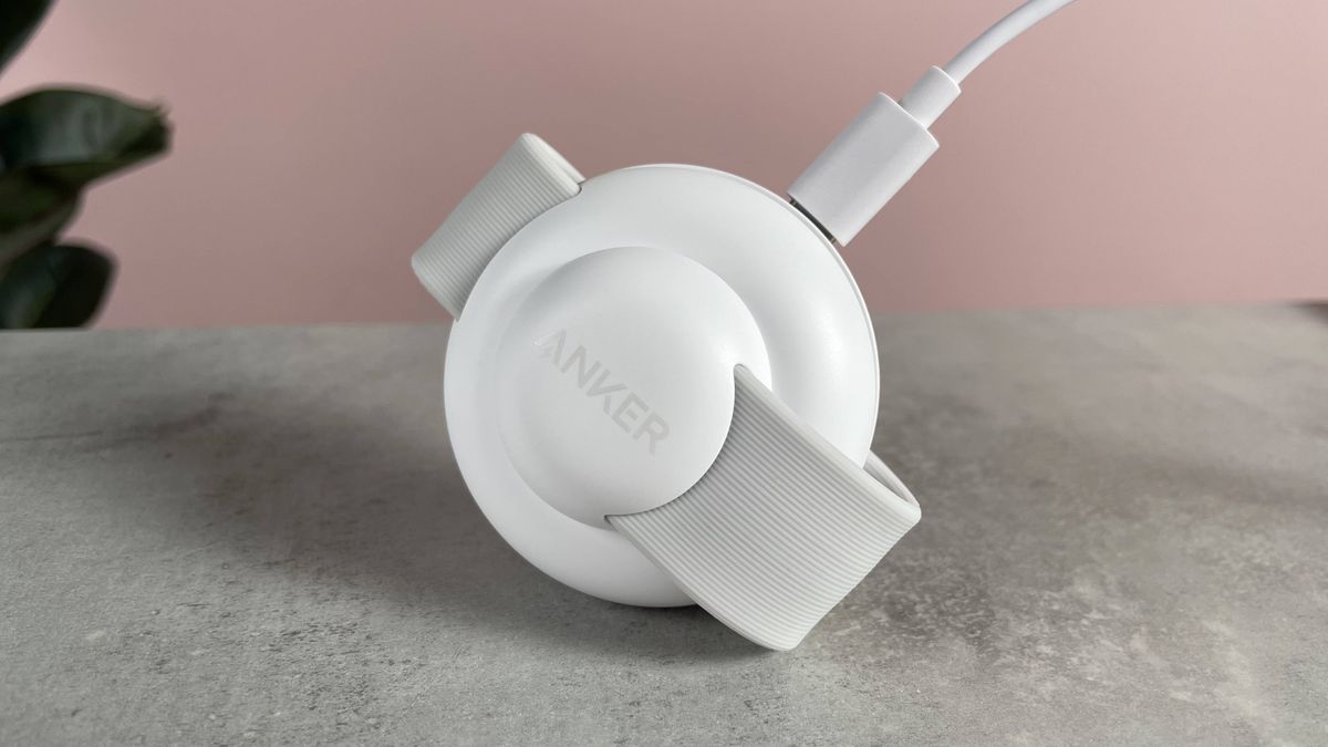 The small Anker charging station is balanced on its front edge. The USB-C power cable is plugged into the port on the back of the charger.