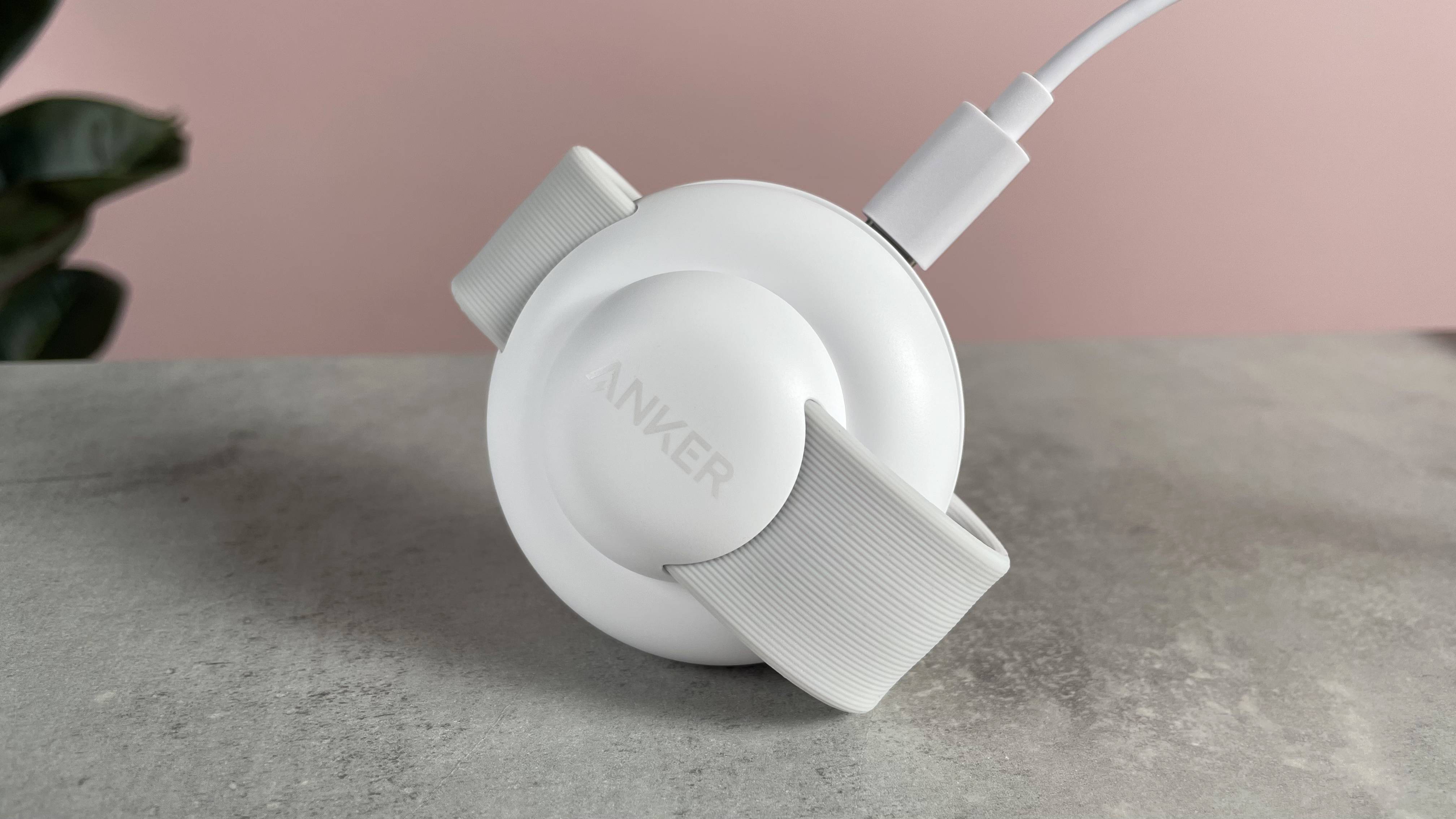 The small Anker charging station is balanced on its front edge. The USB-C power cable is plugged into the port on the back of the charger.