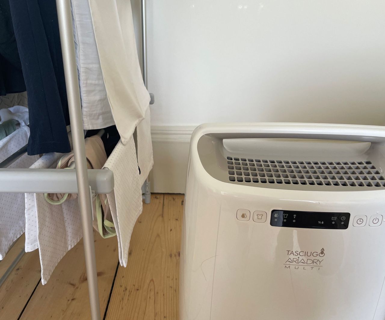 De'Longhi Tasciguo AriaDry 14L dehumidifier beside a clothes horse