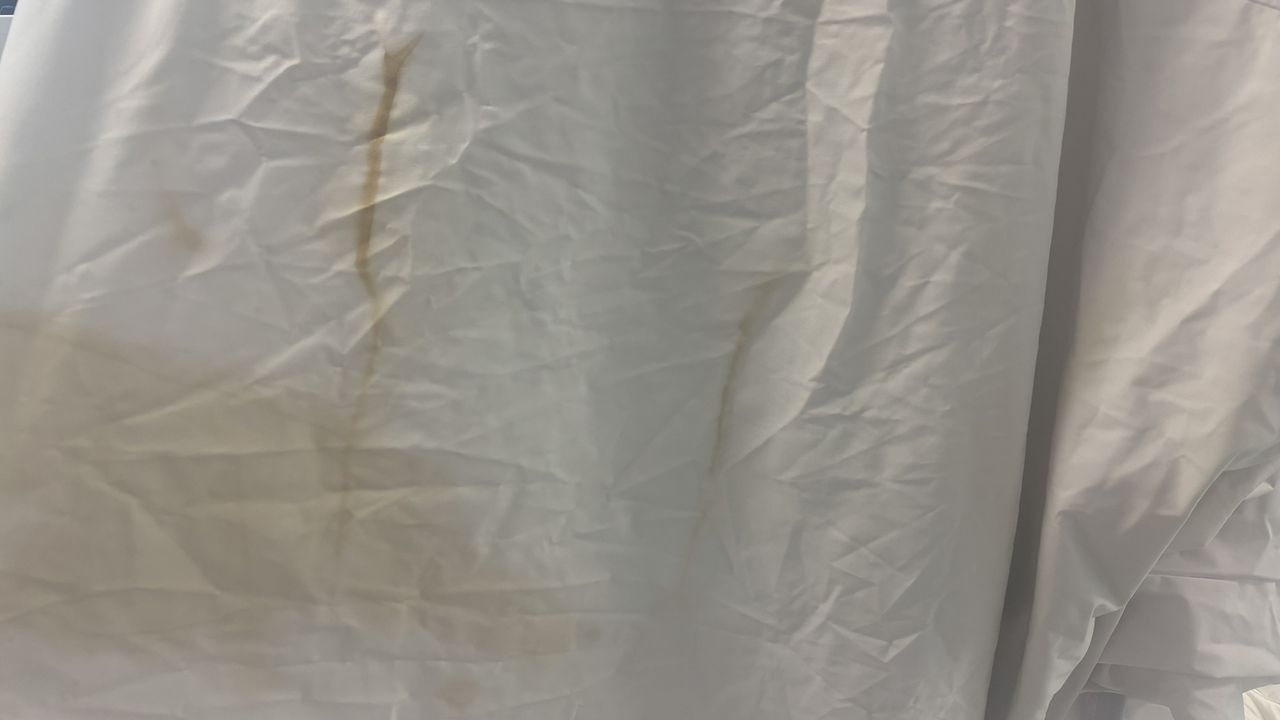 A close up of the Purple Mattress Protector. It shows some light staining from tea and coffee