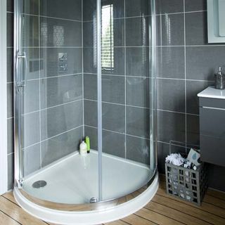 bathroom with grey tiled walls and wooden flooring