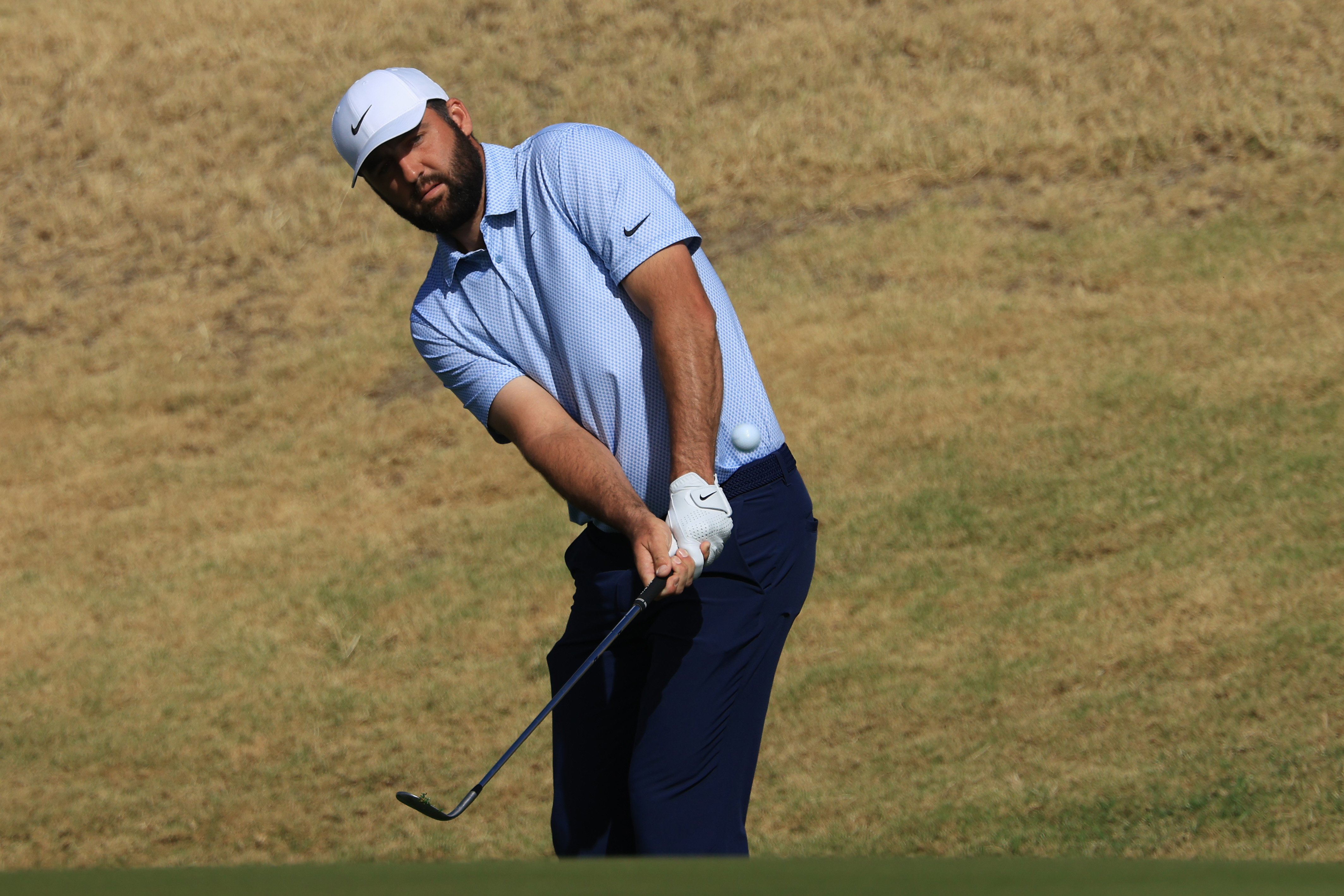 Scottie Scheffler hits a chip shot around the green