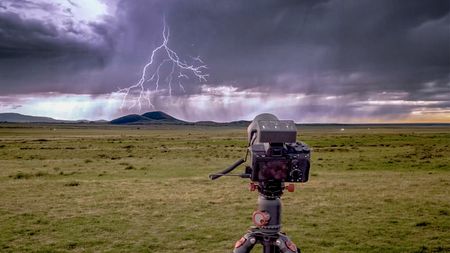 Bolt Hunter mounted on camera on tripod in landscape with bolt of lighting in the sky in distance