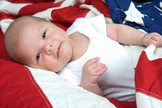 A baby boy laying on an American Flag.