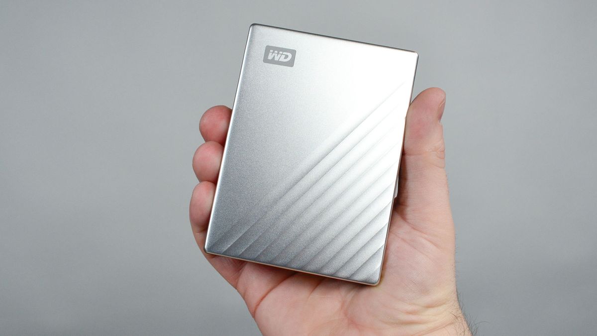 A masculine hand holding a WD My Passport Ultra for Mac