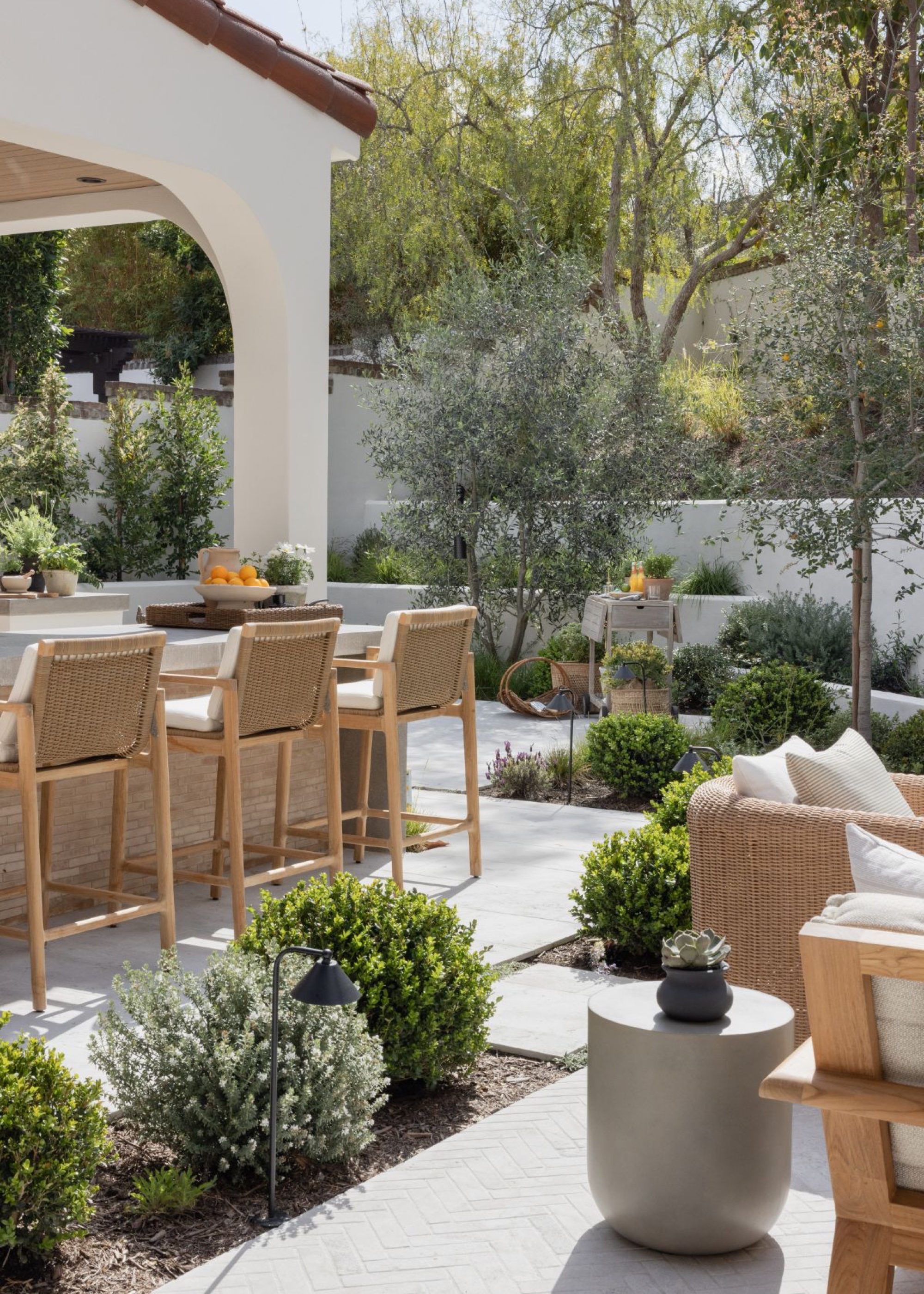 outdoor kitchen and outdoor living room separated by plant boundary with garden furniture in different areas of the garden