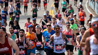 Collection of runners competing in a marathon. They are running on a road and wearing different colored athletic clothing.