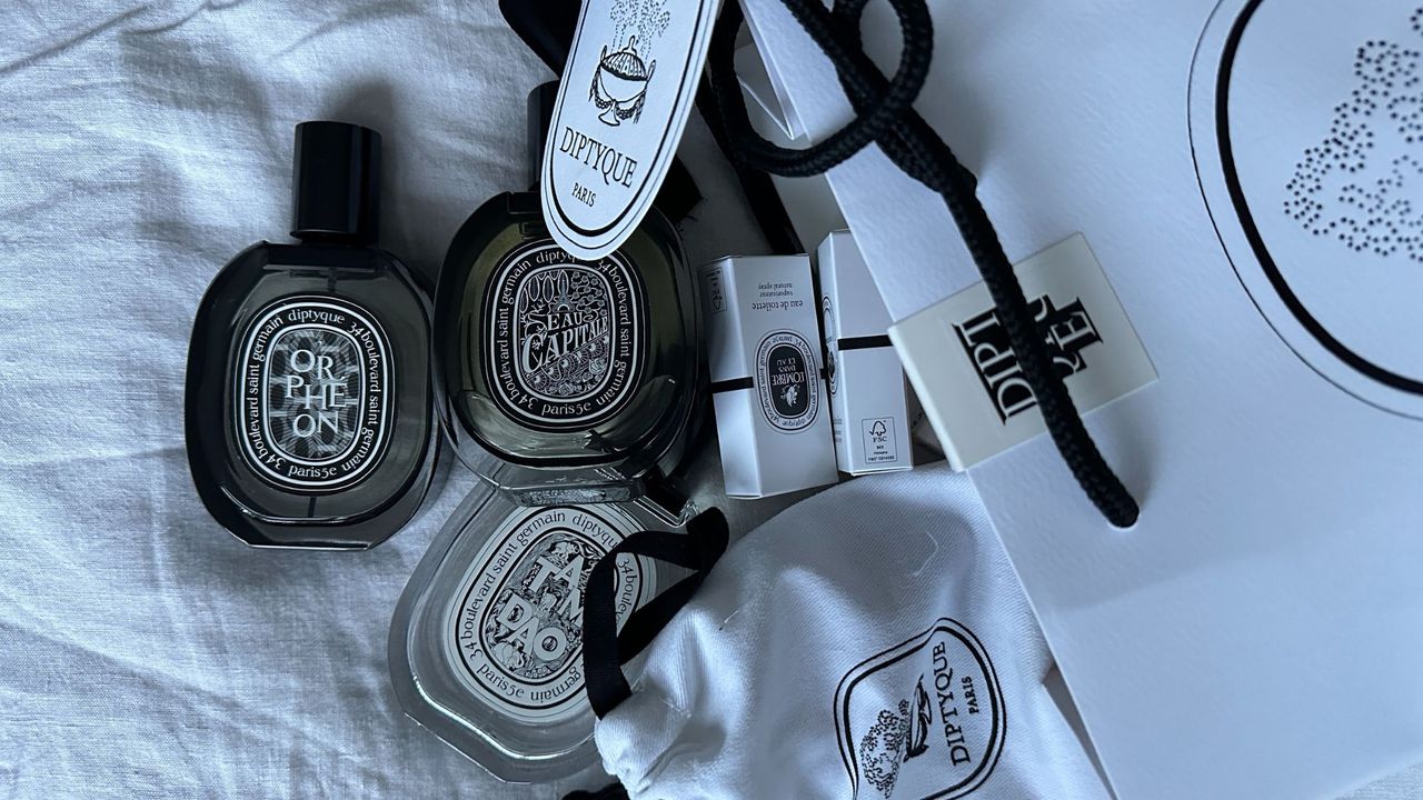 An image of several Diptyque perfumes pouring out of a bag