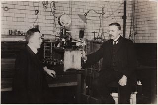 Ernest Rutherford and Hans Geiger next to an alpha particle counting experiment.